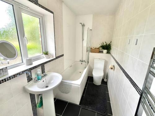a white bathroom with a sink and a toilet at Hydrangea Cottage in St Austell