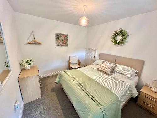 a bedroom with a bed and a wreath on the wall at Hydrangea Cottage in St Austell