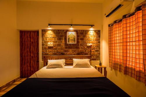a bedroom with a bed and a brick wall at Golden Loom Homestay in Kanchipuram