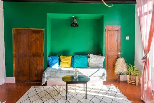 a green room with a couch with colorful pillows at Cool charming appartment in historic forcalquier in Forcalquier