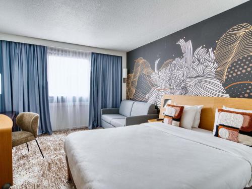 a hotel room with a large bed and a couch at Novotel Paris Charenton le Pont in Charenton-le-Pont
