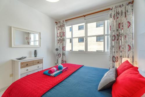 a bedroom with a red and blue bed and a window at Casa Cabana in El Médano