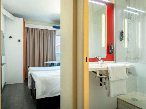 a room with a bed and a sink and a mirror at ibis Bayonne Centre in Bayonne