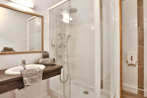 a bathroom with a sink and a shower at Logis Hotel Le Tropicana in Douville