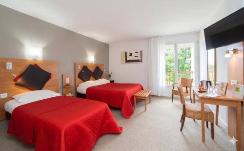 a hotel room with two beds and a table and chairs at Logis Hotel Le Tropicana in Douville