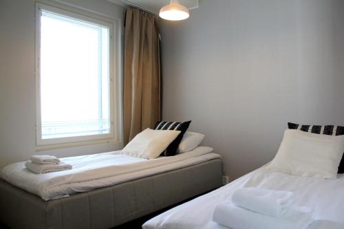 two beds sitting next to a window in a room at Spot Apartments Airport Premium in Vantaa