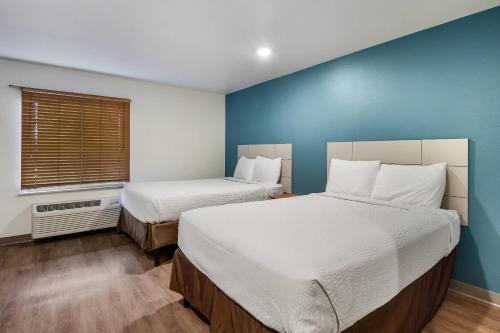 a bedroom with two beds and a blue wall at WoodSpring Suites Abilene in Abilene