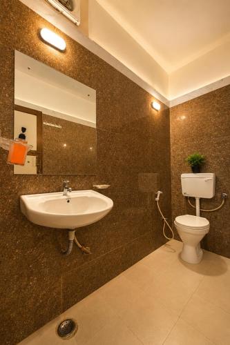 a bathroom with a sink and a toilet and a mirror at Hotel Happy Forest -Boutique Garden Retreat in Mount Abu in Mount Ābu