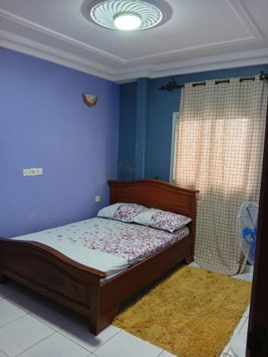 a bedroom with a bed and a blue wall at Palace Ndogbong Bifaga in Bassa