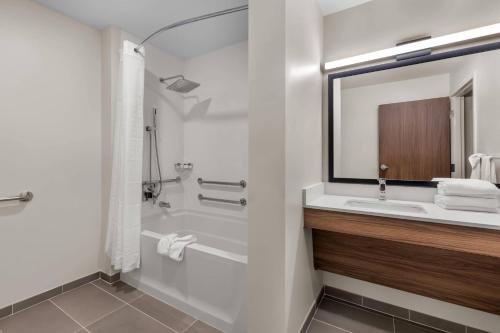 a bathroom with a tub and a sink and a mirror at Everhome Suites Stockbridge Atlanta in Stockbridge