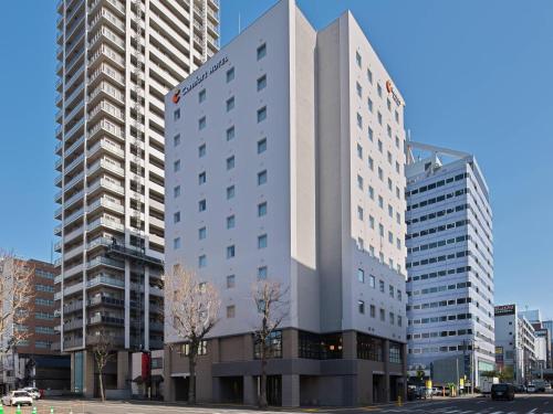 a tall white building on a city street with tall buildings at Comfort Hotel ERA Sapporo North in Sapporo