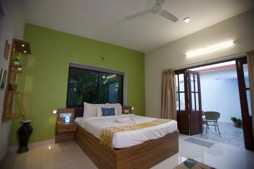 a bedroom with a bed with green walls and a window at 4BHK Villa in Anjuna with Jacuzzi & Pool in Anjuna