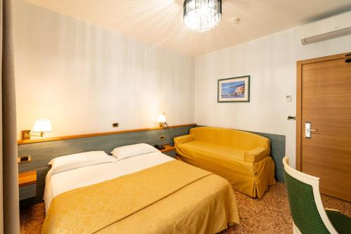 a hotel room with a bed and a chair at Hotel Souvenir in Lido di Jesolo