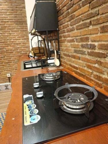 a table with a stove and a tv on a brick wall at Villa Sasandu Termanu in Gadog