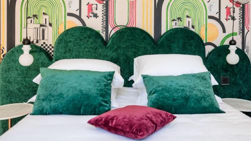 a bed with green and white pillows in a room at La Villa Kara in Romans-sur-Isère