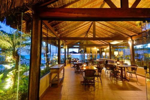 a restaurant with tables and chairs and a view of the ocean at Chez Louise et Louis Pé na Areia in Juquei