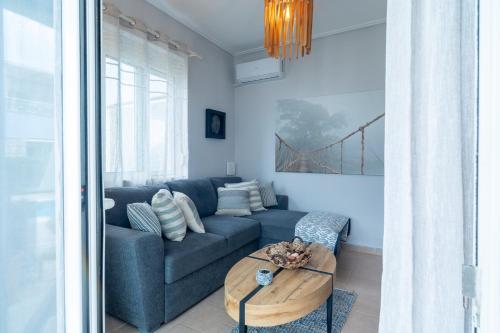a living room with a blue couch and a table at Phoebes Place At Kalamaki Court, 2 Bedroom Villa With A Shared Pool - Fully Refurbished For 2026 in Kalamaki