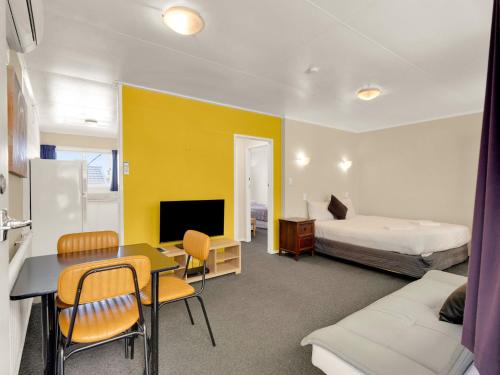 a hotel room with a bed and a table and chairs at Kowhai Motel Rotorua in Rotorua