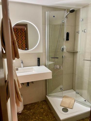 a bathroom with a shower and a sink and a glass shower at Schwarzwaldhotel Klumpp in Baiersbronn