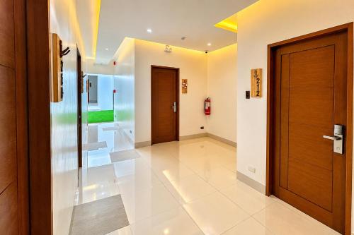 a hallway with wooden doors and white tiles at Lighthouse Point Hotel in Dumaguete