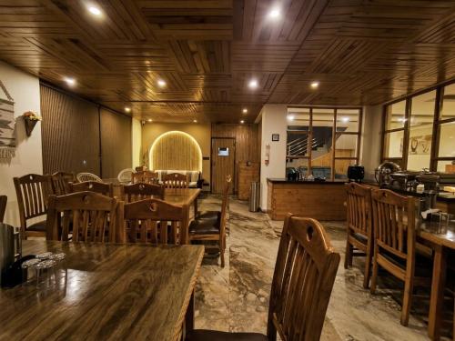 a restaurant with wooden tables and chairs and a counter at Bliss of Heaven in Jagatsukh
