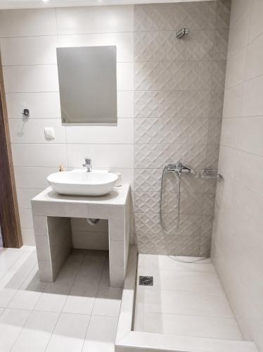 a white bathroom with a sink and a shower at Villa Giannis Apartments in Nea Vrasna