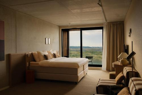 a bedroom with a bed and a couch and a window at Elements Terschelling by Dutchen in Midsland