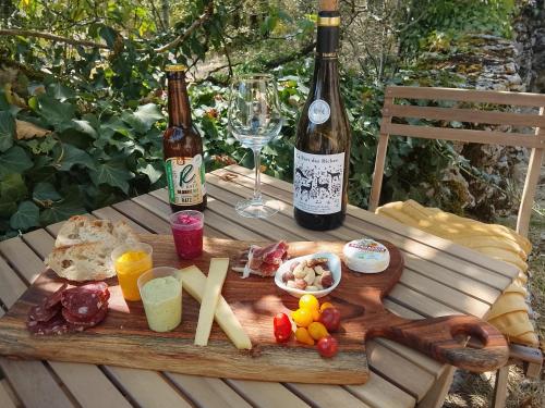 a wooden table with two bottles of wine and food at Marmite et traversin in Cénevières