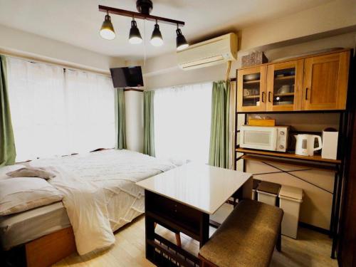 a bedroom with a bed and a table and a microwave at Miyabi Stay Tokyo in Kamatachō