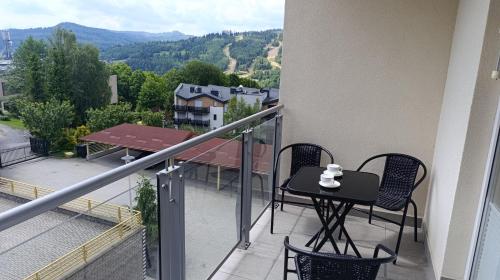 a balcony with a table and chairs on a balcony at LECH Home APARTAMENT NA GÓRZE in Wisła