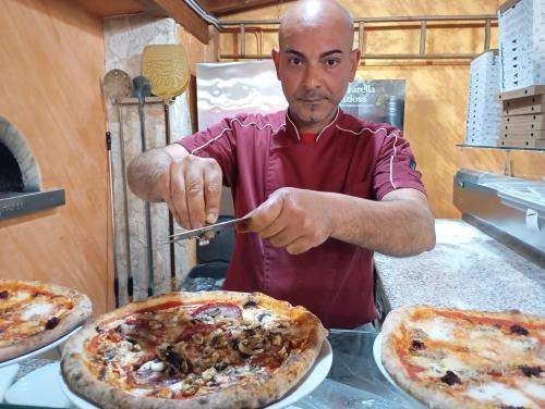 a man is cutting a pizza with a knife at Agriturismo Il Pavone in Torre Lapillo