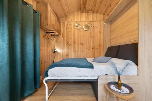 a bedroom with a bed in a room with wooden walls at Ma cabane Océan in Le Verdon-sur-Mer