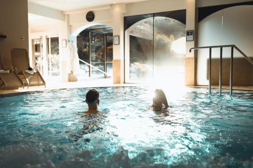 Zwei Personen schwimmen in einem Schwimmbecken in der Unterkunft Vulkanlandhotel Legenstein in Bad Gleichenberg