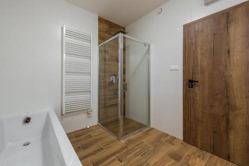 a bathroom with a shower and a wooden door at TATRYSTAY Happy Nest Apartments in Tatranská Lomnica
