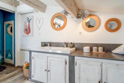 a bathroom with a sink and mirrors on the wall at Mon Cabanon Roquemaure in Roquemaure