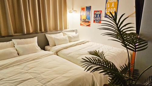 two beds with white sheets and a plant in a room at Hotel Amy in Pup'yŏng-yŏk