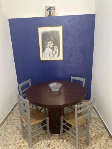 a wooden table with chairs and a painting on a blue wall at Vico Poerio 1 in Tursi