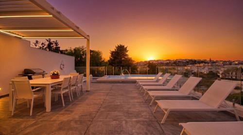 a patio with a table and chairs and a pool at Villa Goa - By Luxury Villas Malta in Mellieħa