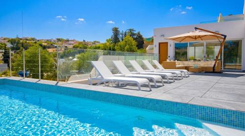 a pool with white lounge chairs and an umbrella at Villa Goa - By Luxury Villas Malta in Mellieħa