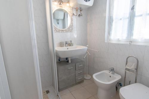 a white bathroom with a sink and a toilet at Appartamenti Seccheto in Seccheto