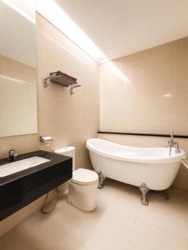 a bathroom with a tub and a toilet and a sink at Scarlet Hotel Stasiun Bandung in Bandung
