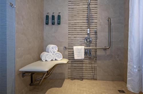 a bathroom with a shower with a bench and towels at DoubleTree by Hilton West Edmonton in Edmonton