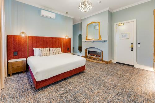 a bedroom with a large bed and a fireplace at Kincraig Hotel in Naracoorte
