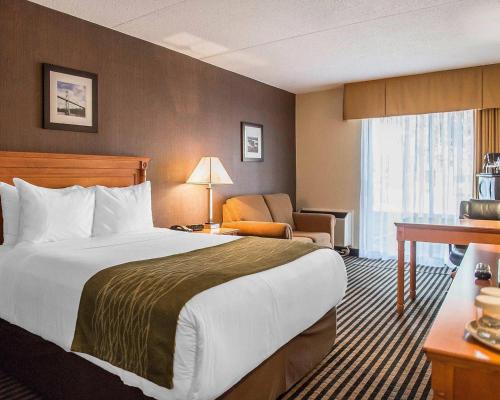 a hotel room with a large bed and a chair at Comfort Inn in Brockville