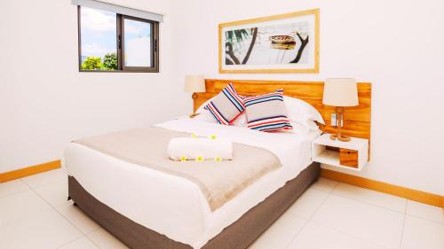 a bedroom with a large white bed with two pillows at Latitude By Horizon Holidays in Rivière Noire