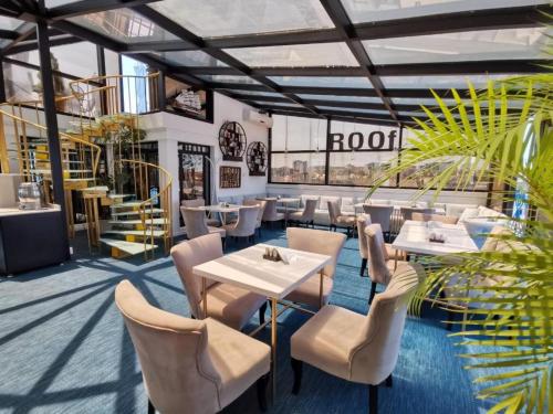 a restaurant with white tables and chairs and plants at Hotel Old Town in Batumi