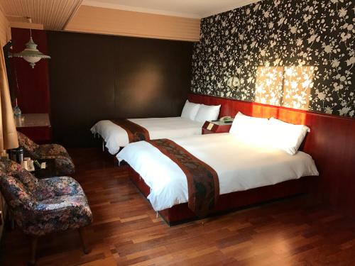 a hotel room with two beds and a chair at Gene Long Haiy Att Hotel in Chiayi City