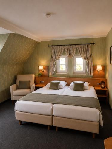 a bedroom with two beds and a chair and two windows at Hotel Altes Rathaus in Ostfildern