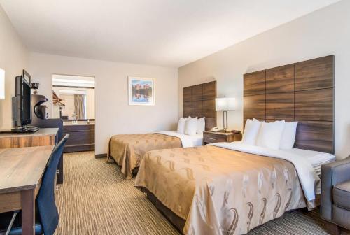 a hotel room with two beds and a desk at Quality Inn Suwanee I-85 in Suwanee