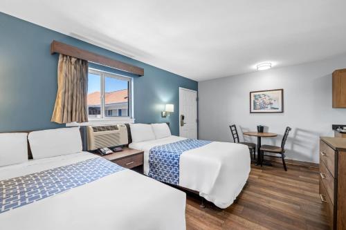 a hotel room with two beds and a table at Suburban Studios Charlotte - Ballantyne in Charlotte